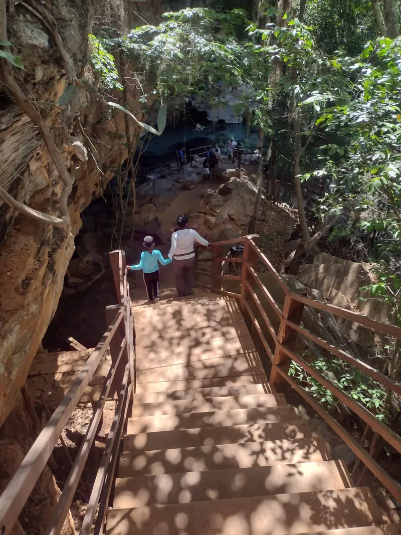 Visitantes descendo a escadaria de madeira que dá acesso à boca de uma gruta na Chapada Diamantina