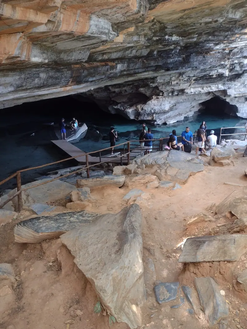 Grupo de visitantes na entrada da Gruta Azul, com a água azul-esverdeada ao fundo, na Chapada Diamantina