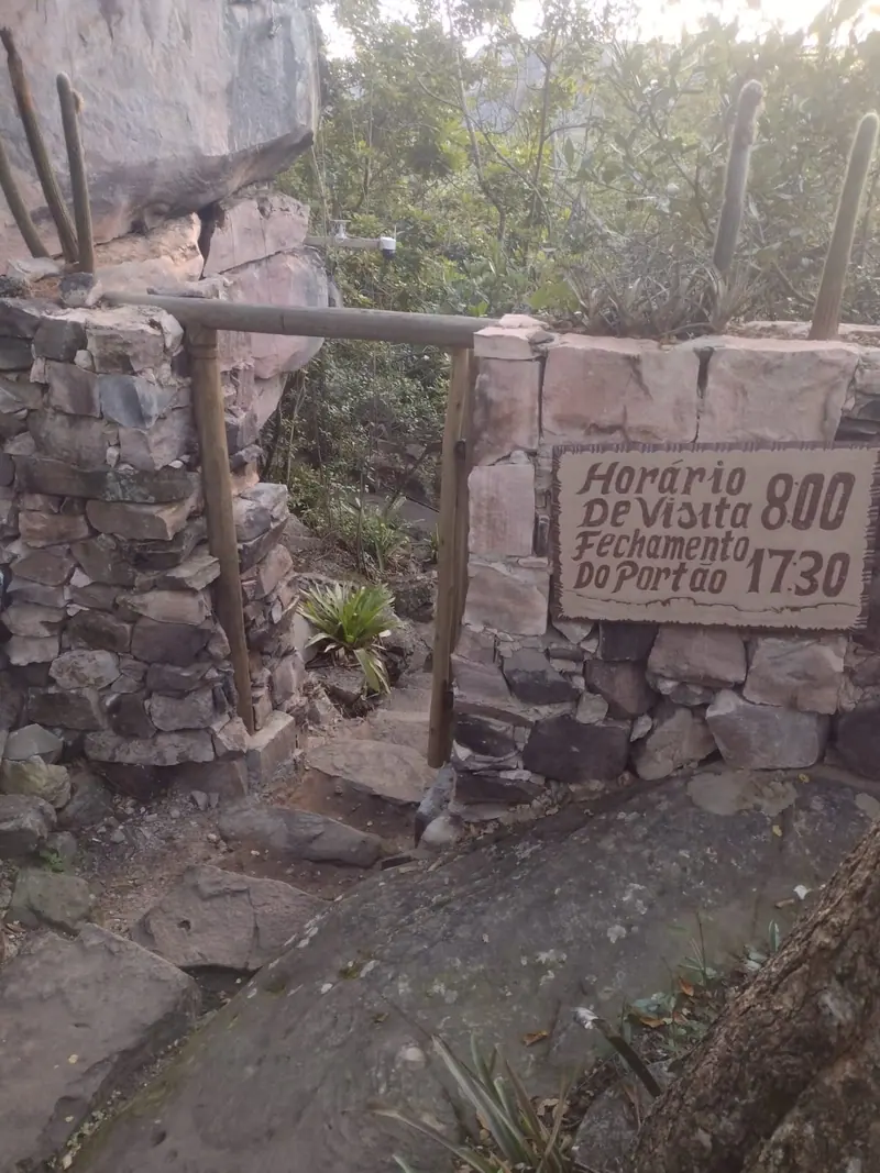 Muro de pedra com placa de horário de visitação em atrativo natural da Chapada Diamantina