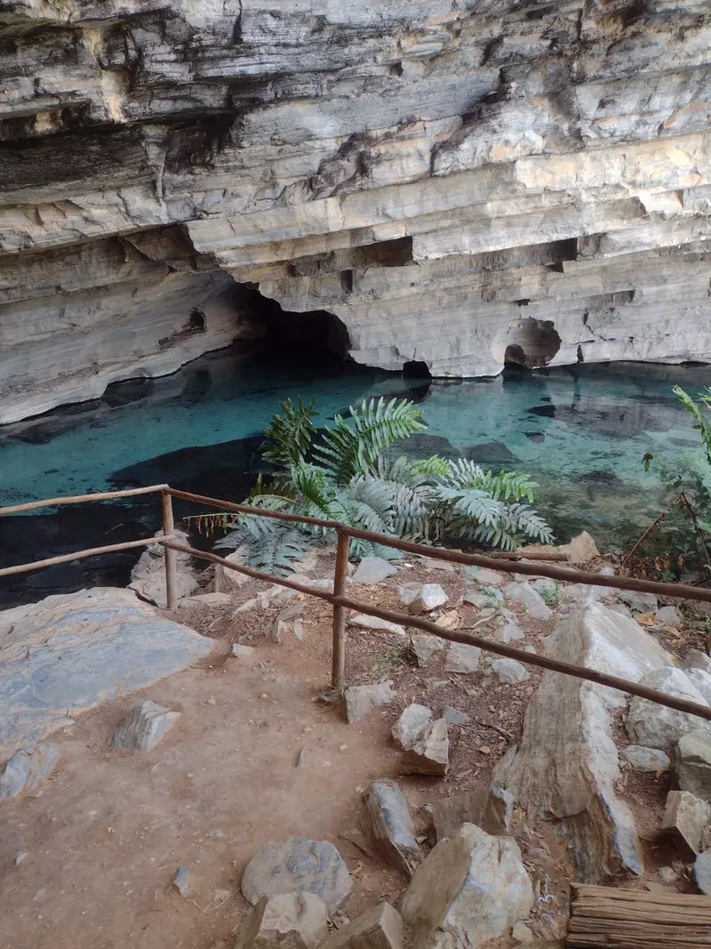 Poço de água azul-turquesa dentro de gruta de paredes calcárias na Chapada Diamantina