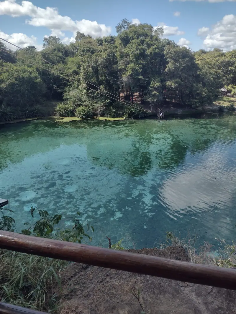 Lago de águas claras da Pratinha com cabo de tirolesa atravessando, cercado de mata